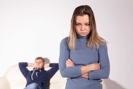 People, domestic violence and abuse concept - Woman with crossed arms and man on the white sofa.