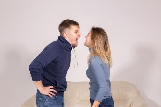 people, domestic violence and abuse concept - young couple arguing indoors.