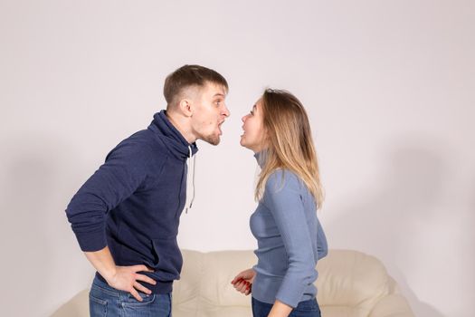 people, domestic violence and abuse concept - young couple arguing indoors.