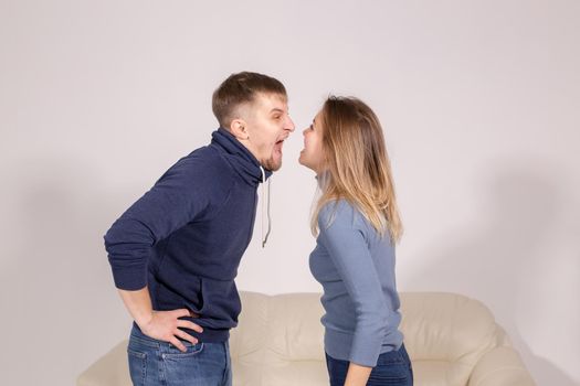 people, domestic violence and abuse concept - young couple arguing indoors.