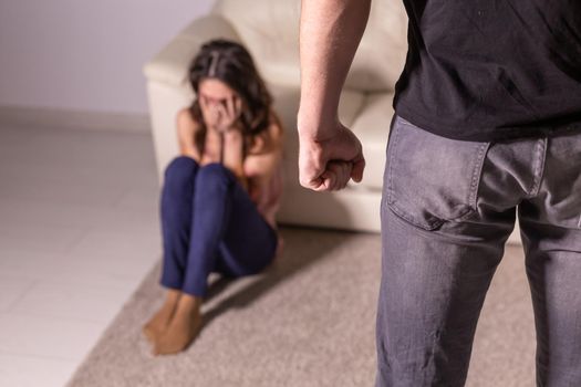 Alcoholism, abuse and domestic violence - Woman lying on the floor. She is afraid of man with bottle.