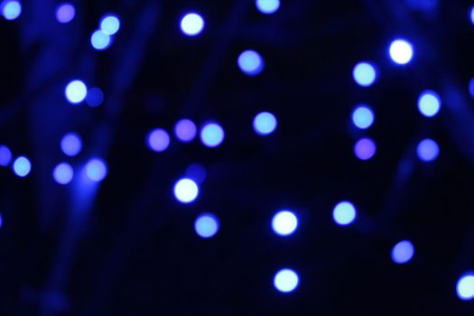 blue blue garlands on a dark black background. New Year's Eve christmas background. Festive lighting.