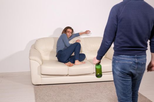 alcoholic, domestic violence and abuse concept - man gets drunk at home and takes his anger at his wife.