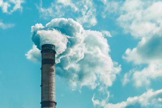 Environmental pollution, environmental problem, smoke from the chimney of an industrial plant or thermal power plant against a cloudy sky.