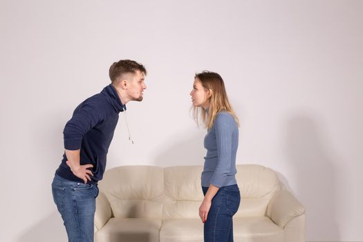 people, home violence and abuse concept - young couple screaming to each other on white background.