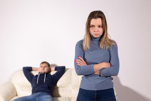 People, domestic violence and abuse concept - Woman with crossed arms and man on the white sofa.