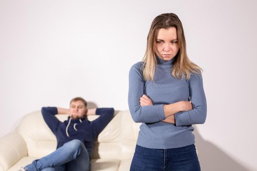 People, domestic violence and abuse concept - Woman with crossed arms and man on the white sofa.