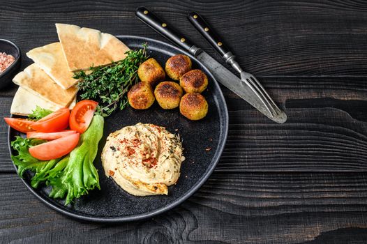 Arabic cuisine Hummus chickpea, falafel, pita bread and fresh vegetables. Black wooden background. Top view. Copy space.