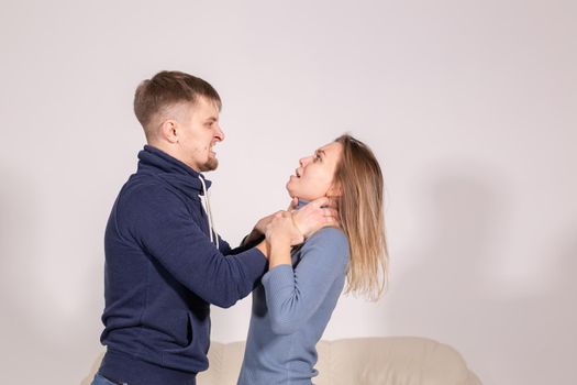 people, domestic violence and abuse concept - young man choked his wife on white background.