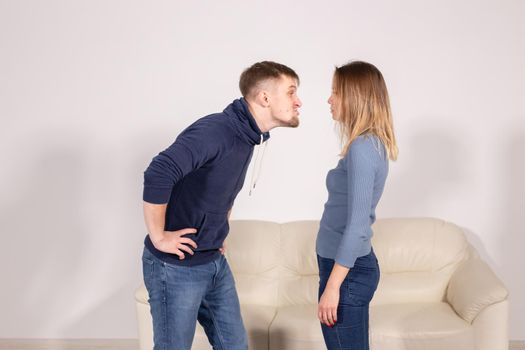 people, home violence and abuse concept - young couple screaming to each other on white background.