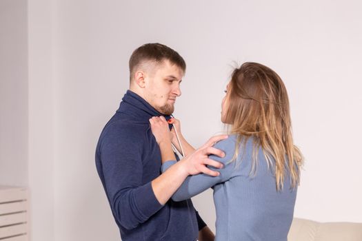 people, domestic violence and abuse concept - young man threatens his wife with his fist on white background.