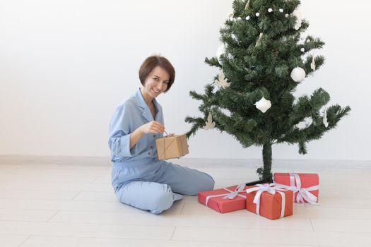 Young woman opens gifts under Christmas tree. Christmas and new year concept.