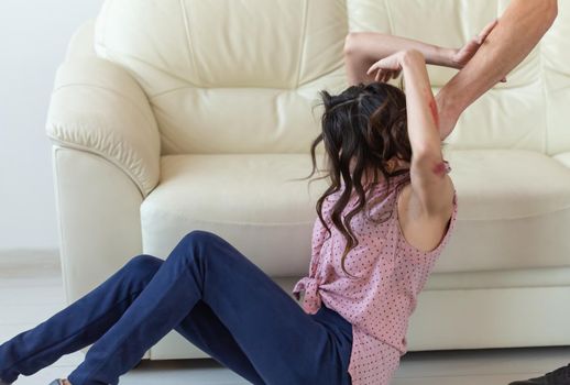 domestic violence, victim and abuse concept - cruel aggressive man grabbing his wife lying on the floor.