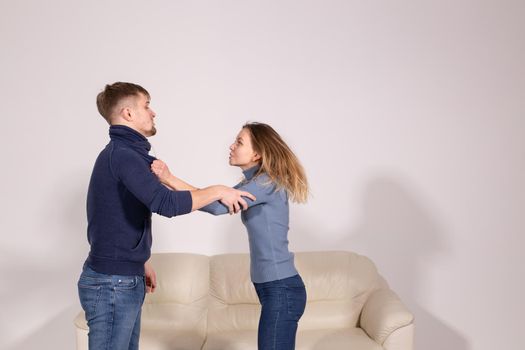 people, violence and abuse concept - young aggressive man hitting his girlfriend in her arm.