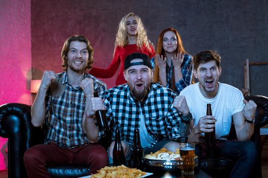 Group of friends watching TV match at home. Football fans on the couch