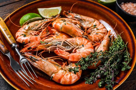 Roasted giant tiger shrimps Prawns on a plate. Dark wooden background. Top view.