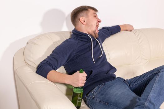 Depression and alcoholism concept - Aggressive male alcoholic sitting on the sofa.
