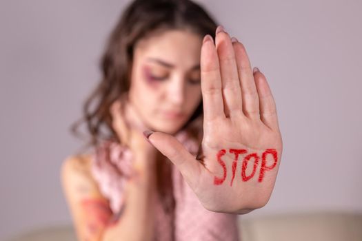 Domestic violence, protesting and people concept - brunette woman expressing denial with STOP on her hand on grey room.