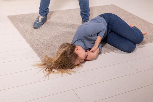 people, abuse and violence concept - woman threatened by husband lying on floor.