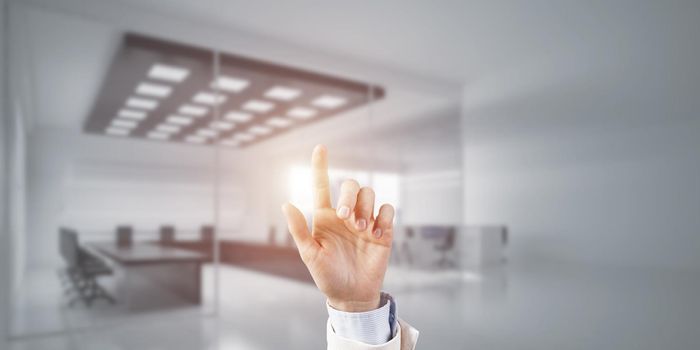 Close of businesswoman hand touching screen with finger and office at background