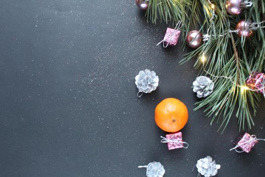 a branch of spruce spruce Christmas trees next to the tangerine cones and lights. Top view with space for text and copyspace. Background Christmas New Year.