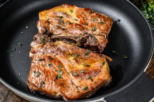 Fried pork loin steaks in a pan. Dark wooden background. Top view.