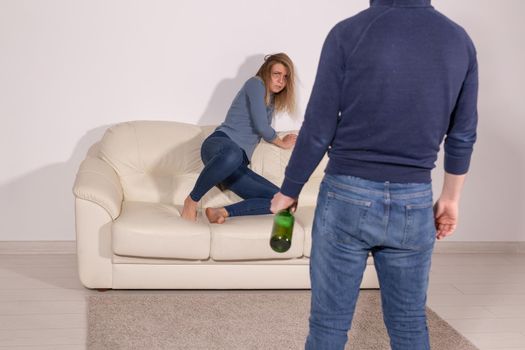 alcoholic, domestic violence and abuse concept - man gets drunk at home and takes his anger at his wife.