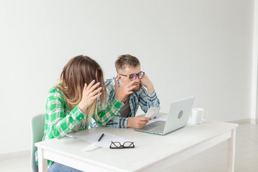 Concentrated husband and wife count purchases and bills for the past month and record the results in their home bookkeeping in a notebook and on a laptop. Concept of saving and accounting