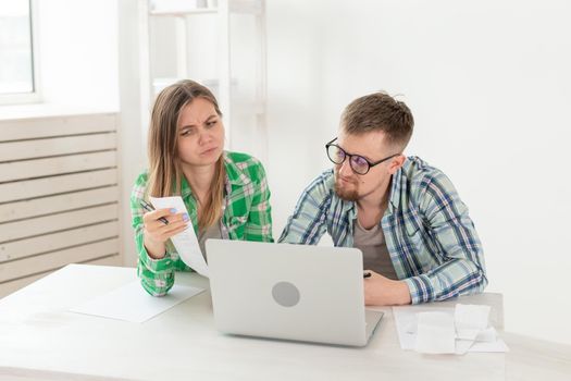 Concentrated husband and wife count purchases and bills for the past month and record the results in their home bookkeeping in a notebook and on a laptop. Concept of saving and accounting