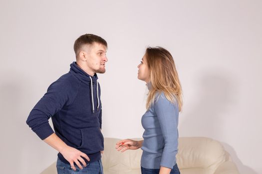 people, domestic violence and abuse concept - young couple arguing indoors.