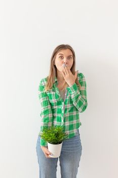 bikini hair removal, excess hair removal - a shocked woman holds a bush in a pot. She is terrified of the amount of excess hair on her body