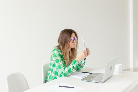 Upset young woman considers the amount of expenses for purchases and payment of credits by entering information into laptop for accounting of home bookkeeping. Concept of savings and waste