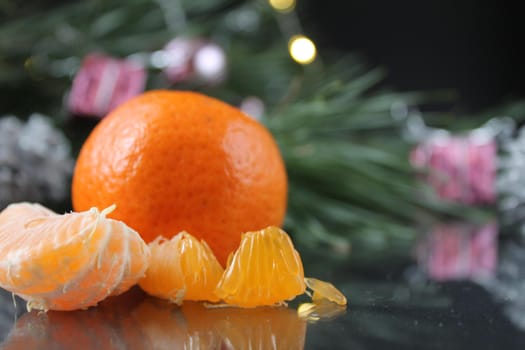 mandarin and slices of mandwrin lie near the Christmas tree with cones and lights. New Year's atmosphere.