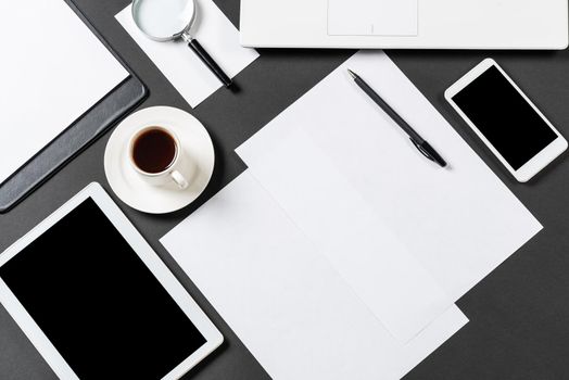 Top view of designer workplace with modern digital devices. Flat lay stylish design with black surface and copy space. Digital technology and mobile lifestyle. Laptop, tablet computer and smartphone.