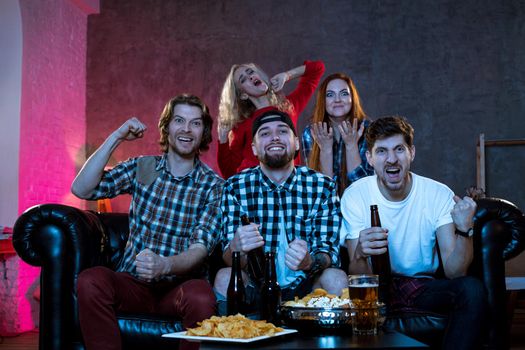 Group of friends watching TV match at home. Football fans on the couch