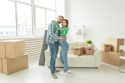 Loving young couple embracing rejoicing in moving to their new home. The concept of moving and housewarming of young family