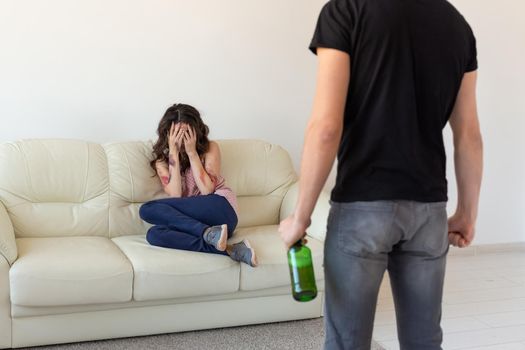 alcoholic, domestic violence and abuse concept - man gets drunk at home and takes his anger at his wife.