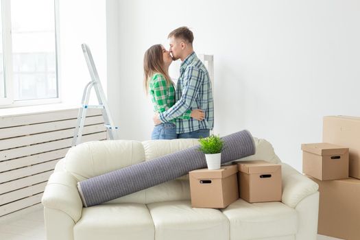 Young couple in denim pants embracing rejoicing in their new apartment during the move. The concept of housewarming and credit for new housing