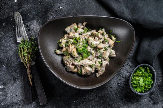 Beef stroganoff with mushrooms in a plate with cremini and champignons. Black background. Top view.