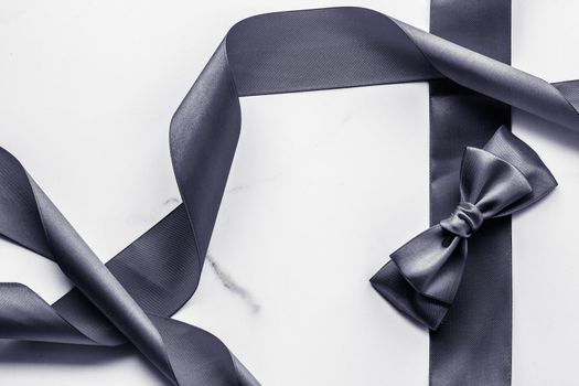 Holiday gift, decoration and sale promotion concept - Black silk ribbon and bow on marble background, flatlay