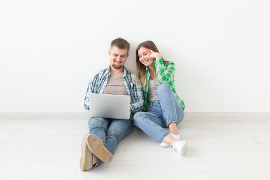Happy young family surfs Internet in search of online stores of furniture and accessories for an apartment with the help of a laptop and Wi-Fi internet. Online shopping and housewarming concept