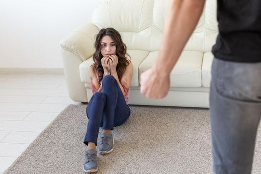 Victim, domestic violence and abuse concept - man threatening with fist to crying woman on floor scared and terrified in domestic violence.