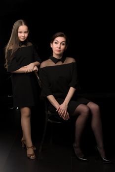 Happy family mom and daughter in the studio on a black background. The concept of love, childhood.