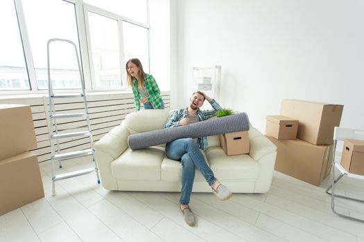 Positive crazy cheerful couple rejoices in moving their new apartment sitting in the living room with their belongings. Concept of housewarming and mortgages for a young family