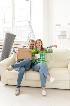 Positive crazy cheerful couple rejoices in moving their new apartment sitting in the living room with their belongings. Concept of housewarming and mortgages for a young family