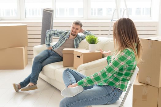 Positive crazy cheerful couple rejoices in moving their new apartment sitting in the living room with their belongings. Concept of housewarming and mortgages for a young family