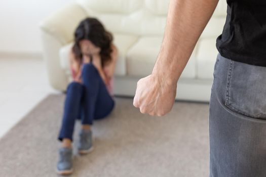 Victim, domestic violence and abuse concept - man threatening with fist to crying woman on floor scared and terrified in domestic violence.