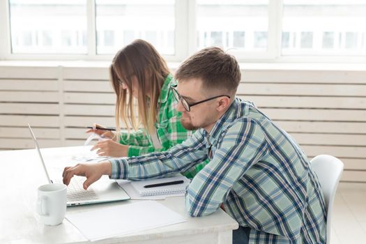 Young husband and wife are upset about numerous checks for payments and purchases for repairs while sitting at the table with a laptop. The concept of low living standards and savings. Copyspace