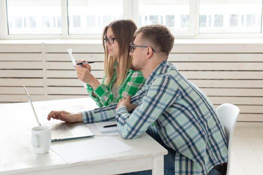 Concentrated husband and wife count purchases and bills for the past month and record the results in their home bookkeeping in a notebook and on a laptop. Concept of saving and accounting