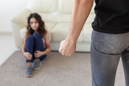 Victim, domestic violence and abuse concept - man threatening with fist to crying woman on floor scared and terrified in domestic violence.